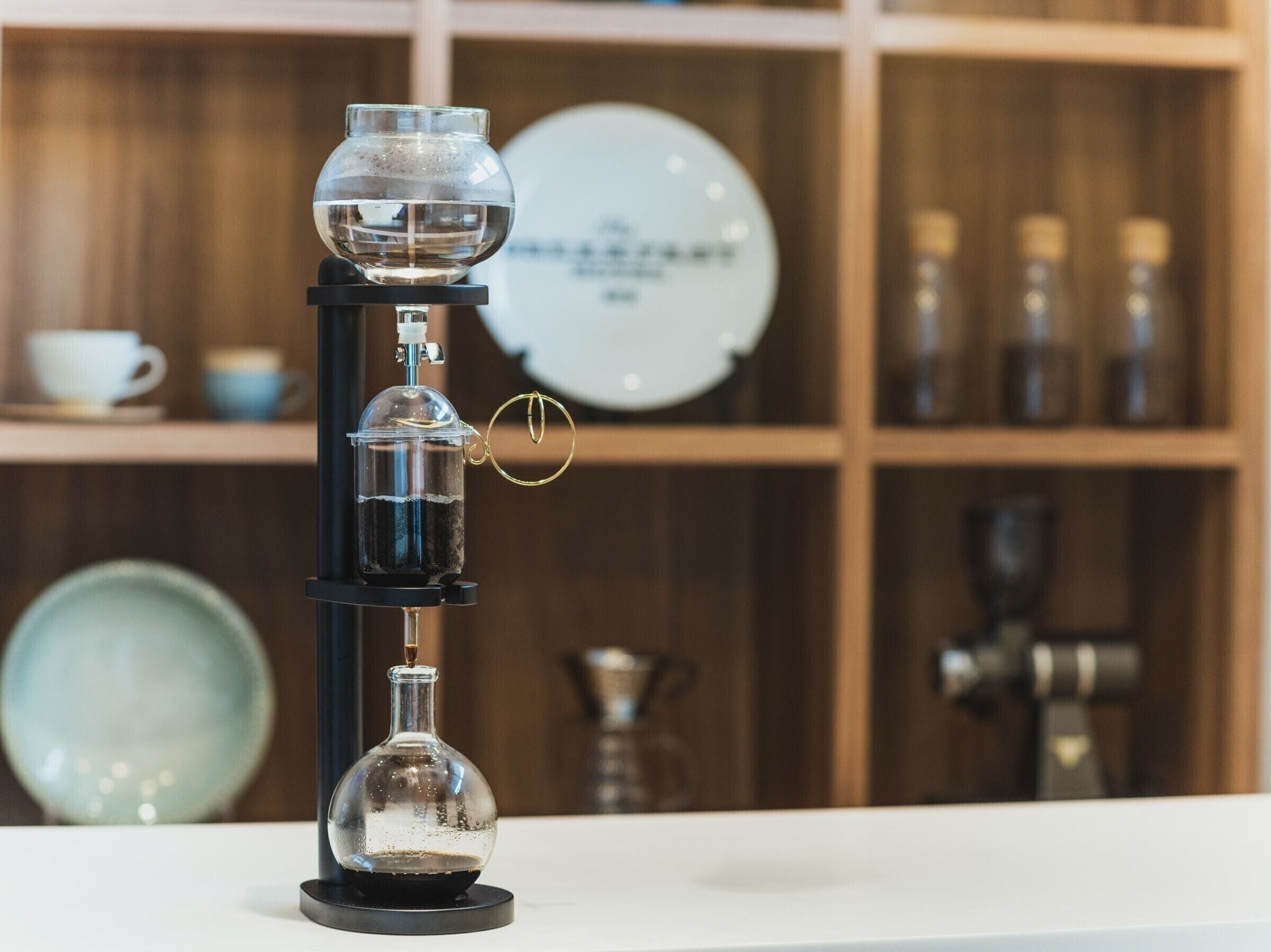 A coffee machine with a glass carafe and a drip coffee maker on a white countertop.