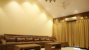 A modern living room with a brown sofa, two wooden coffee tables, and a ceiling fan. - SkyWater Villas And Lifestyle (Igatpuri)