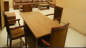 A conference room with a long wooden table, six chairs, a sofa, and a small coffee table. - SkyWater Villas And Lifestyle (Igatpuri)