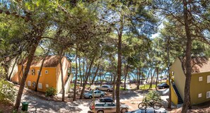 A coastal area with parked cars, a bicycle, and buildings with red-tiled roofs. - Zelena Punta (Kukljica)