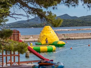 A water park with inflatable slides and a large yellow water slide. - Zelena Punta (Kukljica)