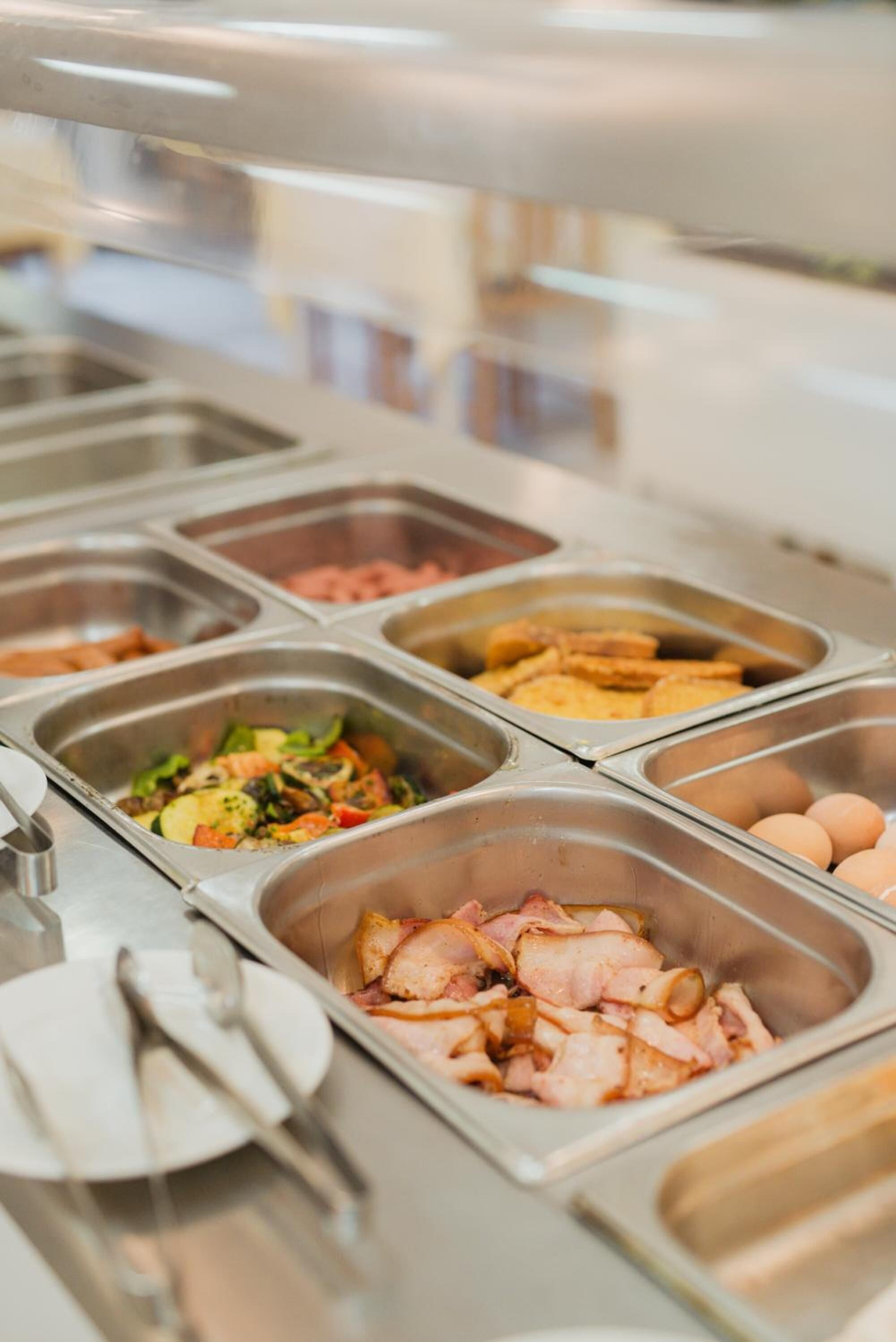 Buffet-pöydässä on tarjolla monipuolinen valikoima ruokia, kuten salaatteja, lihaa ja kananmunia.