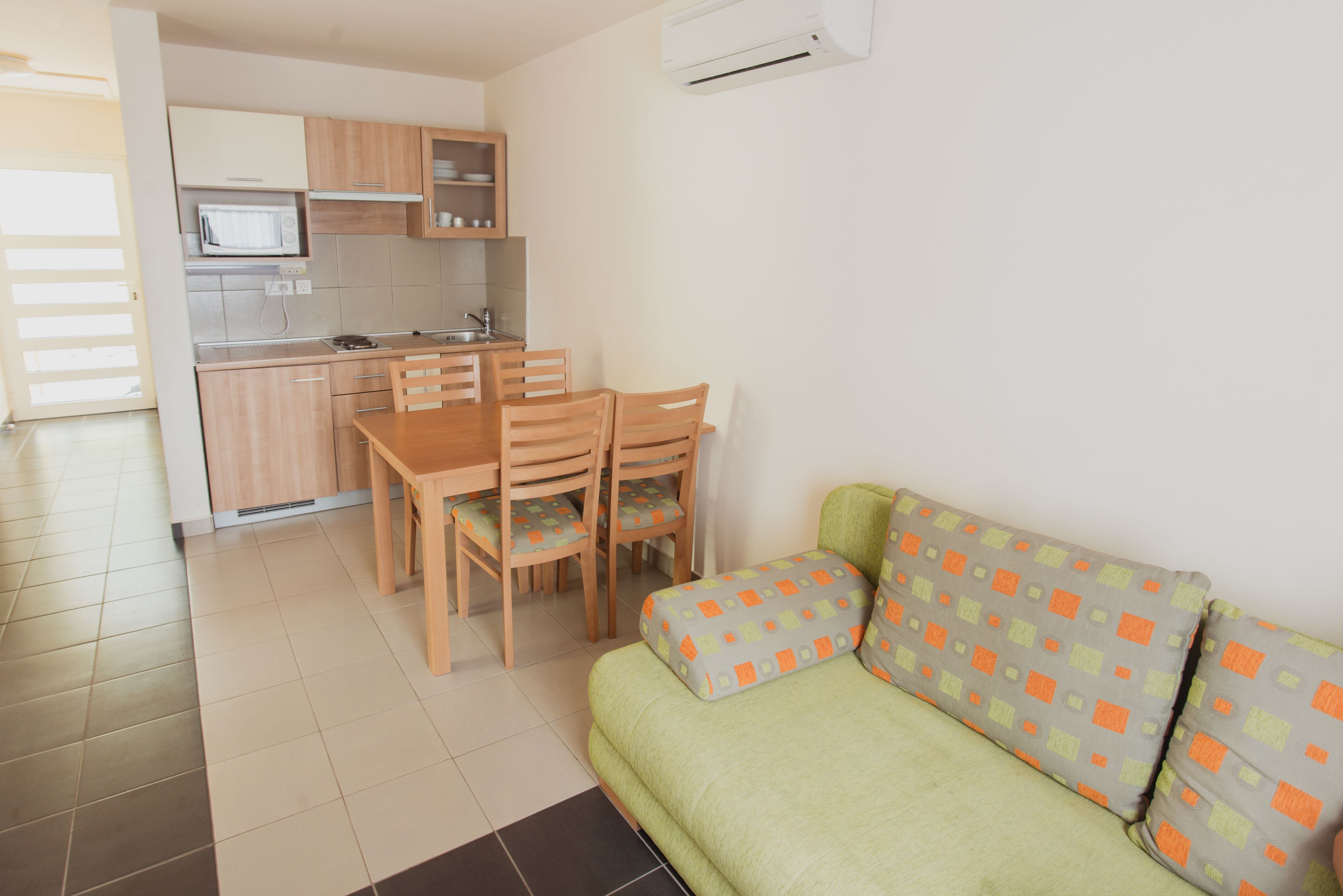 Un espacio habitable compacto con kitchenette, comedor y sofá con cojines estampados.