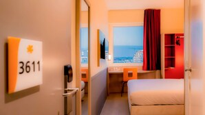 A hotel room with a bed, a desk, a chair, a TV, a window with a view of the city, and a red curtain. - Hotel Première Classe Casablanca Centre Ville (Casablanca)