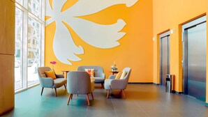 A modern lobby with a large abstract wall art, a seating area with chairs, and an elevator. - Hotel Première Classe Casablanca Centre Ville (Casablanca)