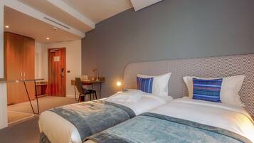 A modern hotel room with a large bed, a desk, and a chair.