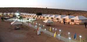 Un resort en el desierto con varias tiendas de campaña y un edificio central con piscina.