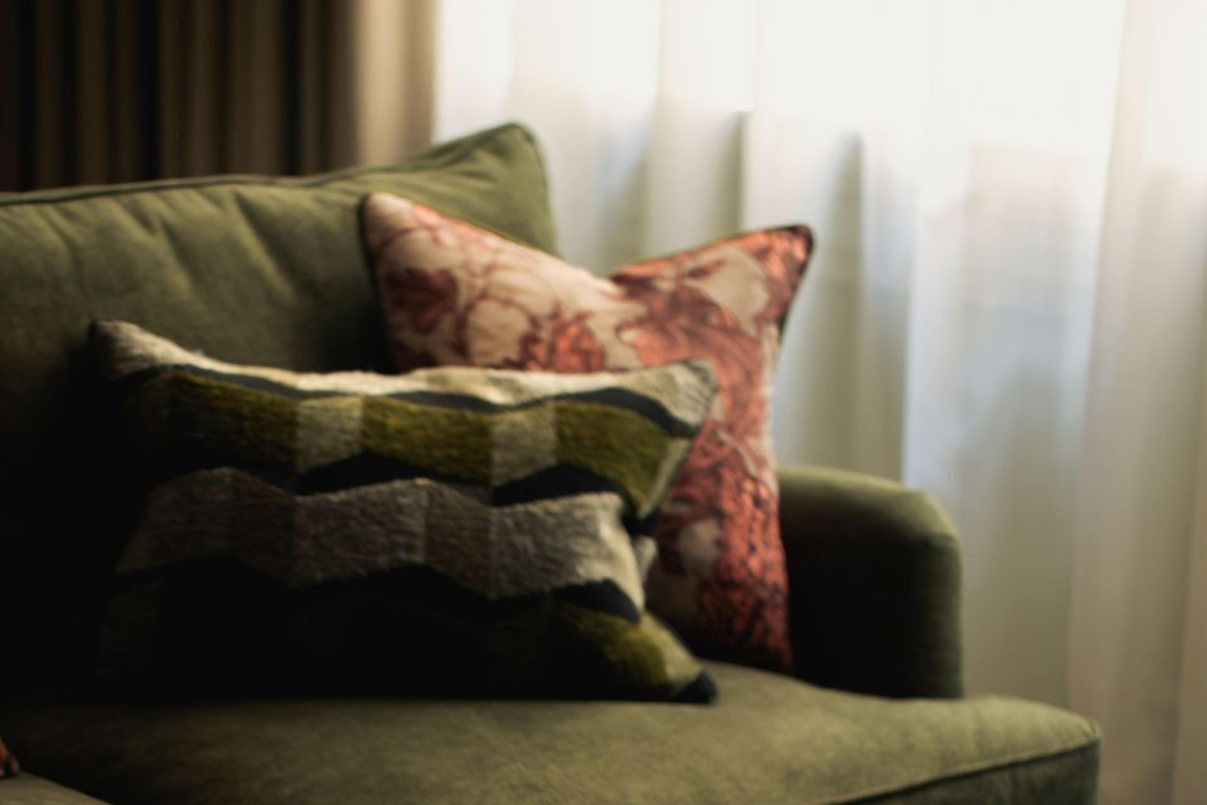 A green armchair with multiple decorative pillows.