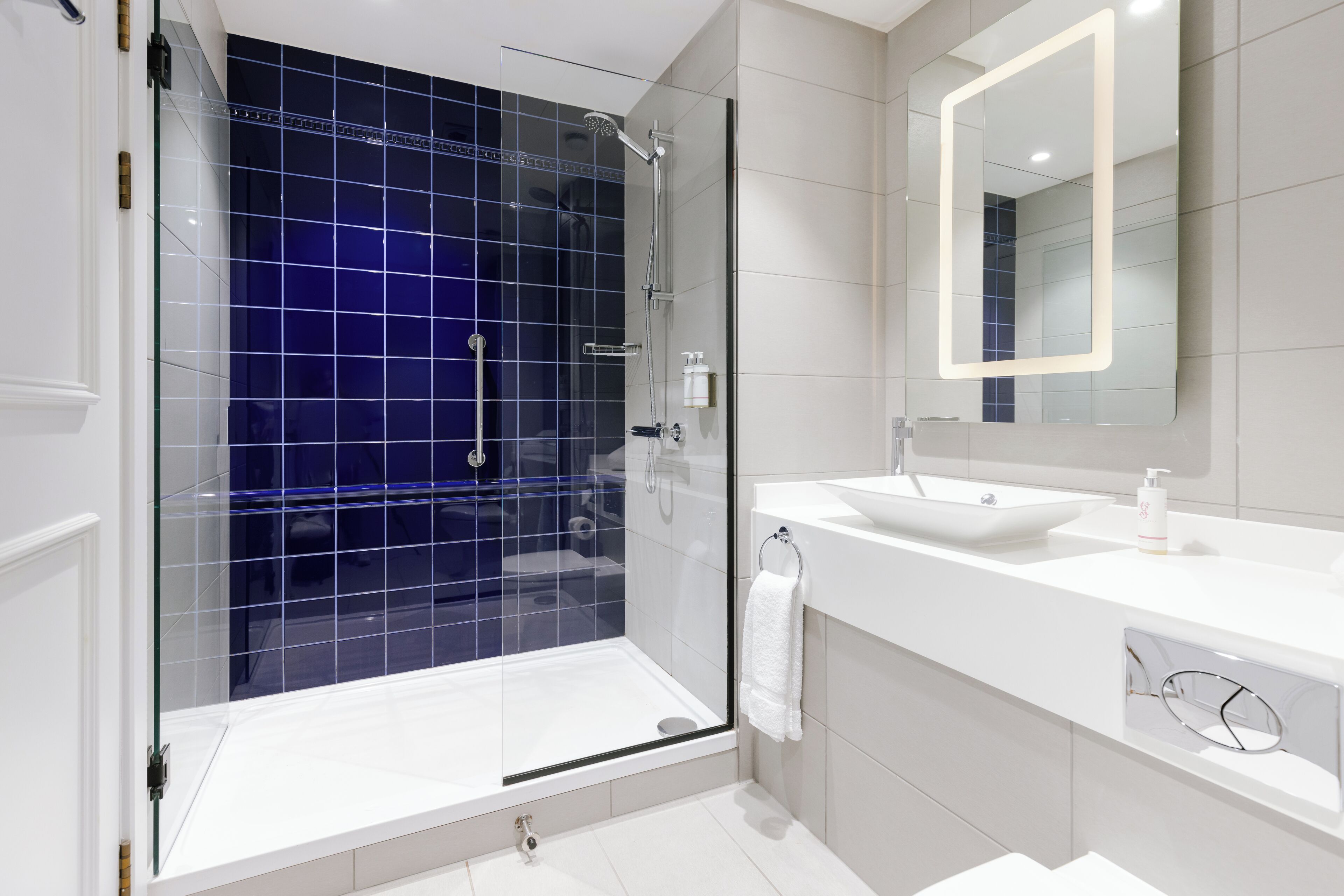 A modern bathroom with a glass-enclosed shower, a white sink, and a large mirror.