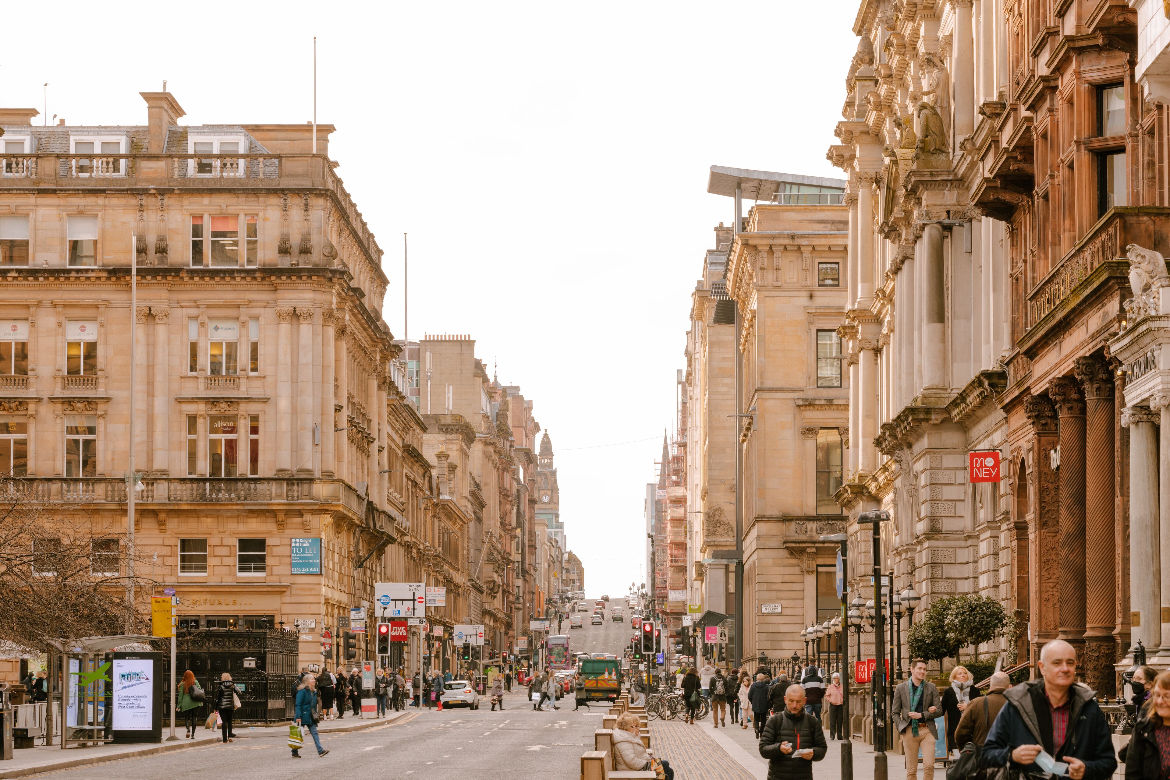A street view with historic buildings, a bus, and pedestrians.