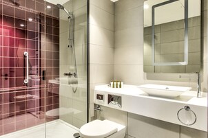 A modern bathroom with a glass-enclosed shower, a white sink, and a mirror above the sink.