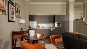 A modern kitchen with dark wood cabinets, a microwave, and a dining area with a round table and orange chairs.