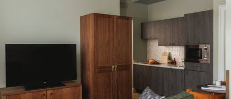 A living room with a TV, wooden wardrobe, and a green sofa.