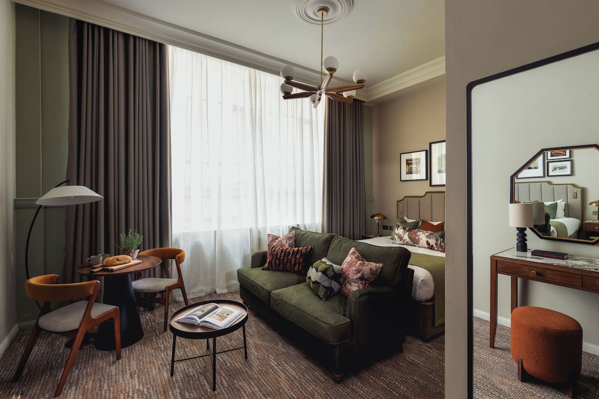 Uma sala de estar moderna com um sofá verde, duas poltronas, uma mesa de centro e um espaço de jantar com uma planta.