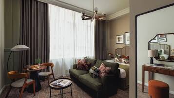 Una sala de estar moderna con un sofá verde, dos sillones, una mesa de centro y un comedor con una planta.