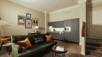 A living room with a green sofa, a coffee table, and a kitchen area in the background.