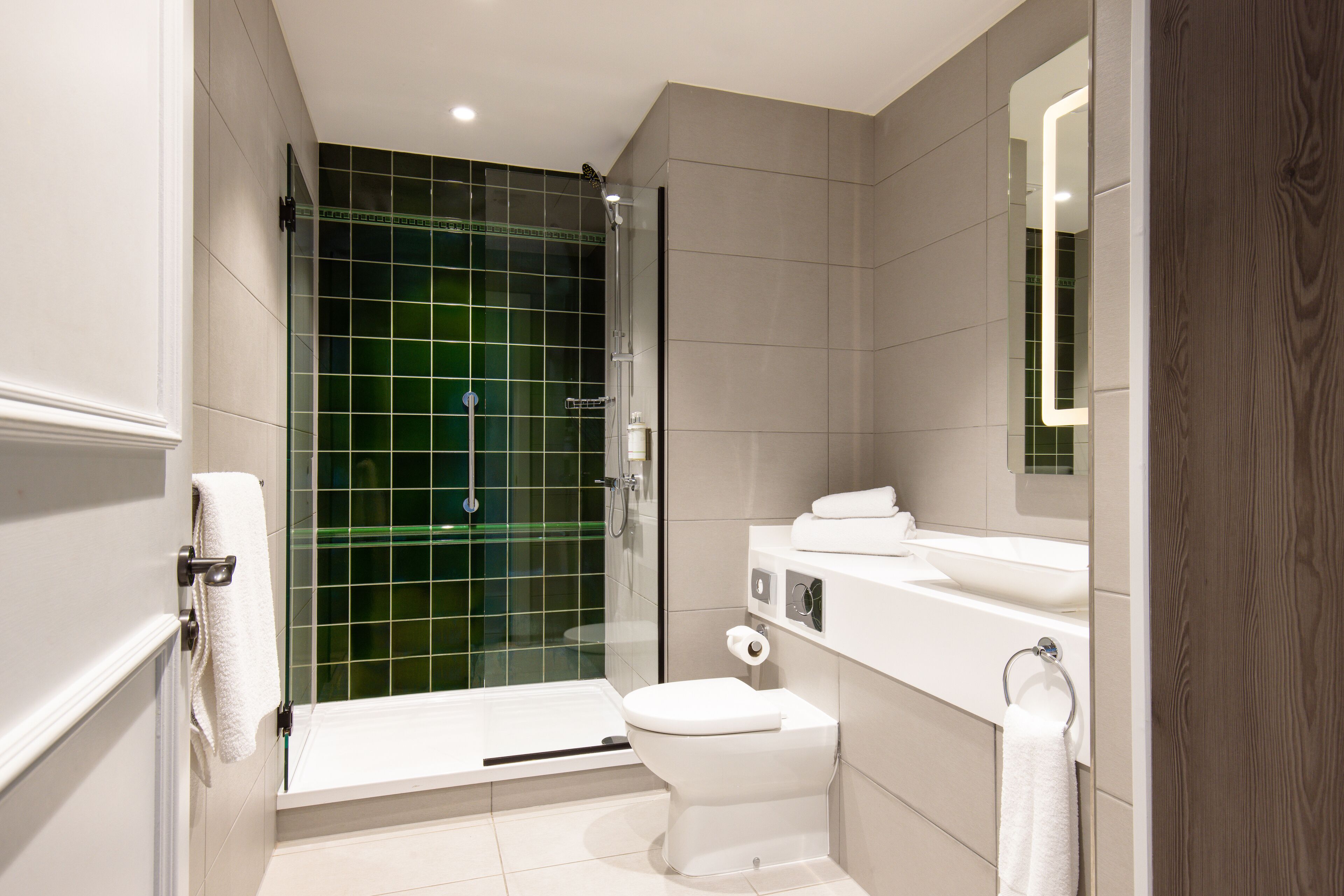 A modern bathroom with a glass shower enclosure, a white toilet, and a vanity with a mirror.