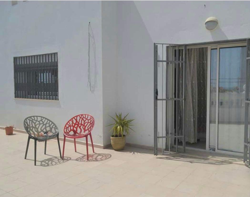 A patio with two chairs, a potted plant, and a sliding glass door.