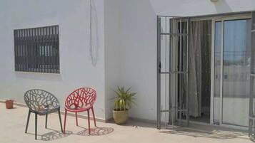 A patio with two chairs, a potted plant, and a sliding glass door.