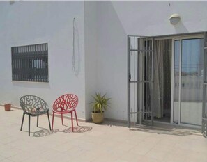A patio with two chairs, a potted plant, and a sliding glass door. - Villa (Hammamet)