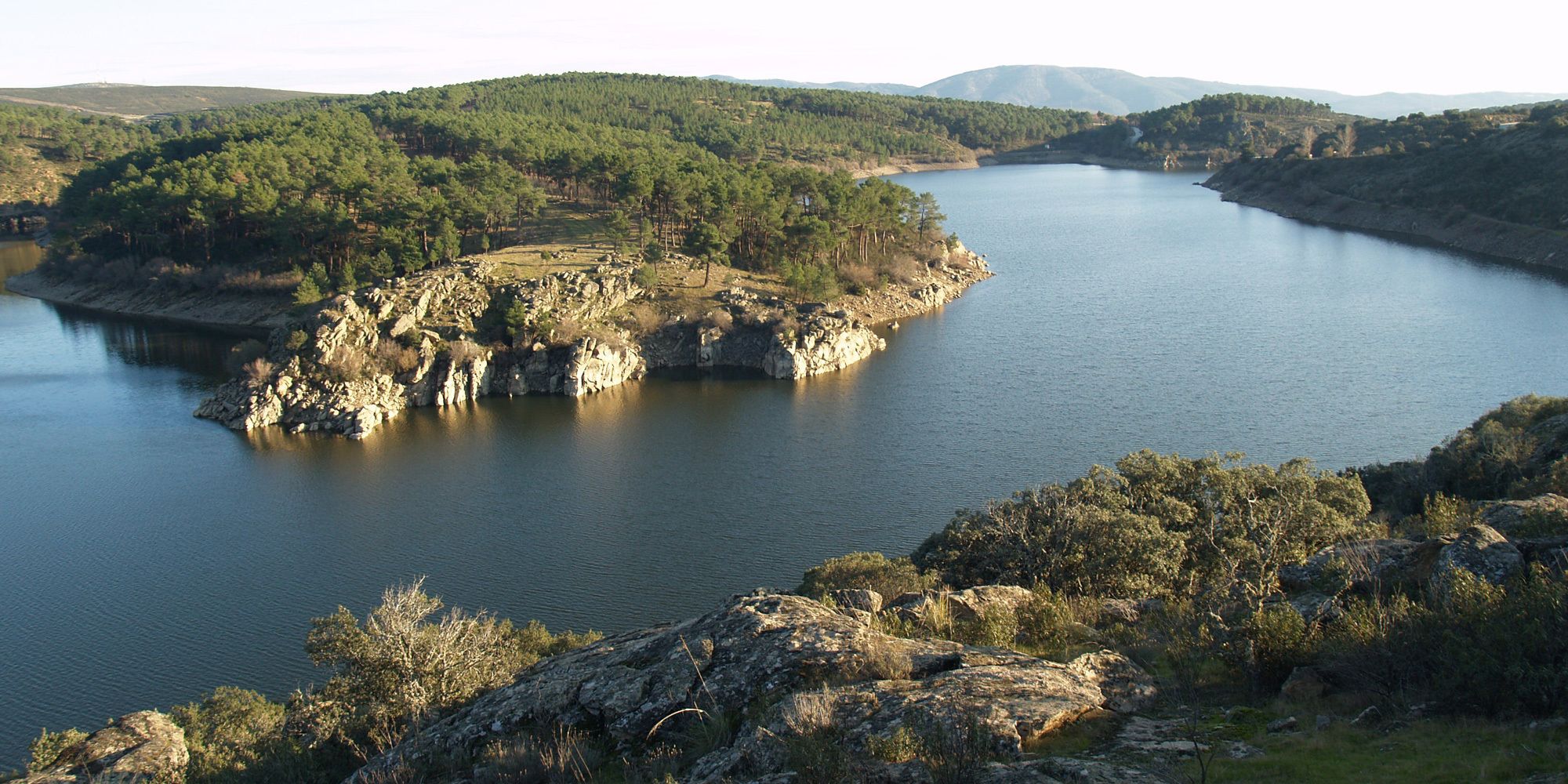 A river winding through a mountainous landscape with rocky outcrops and dense forests.