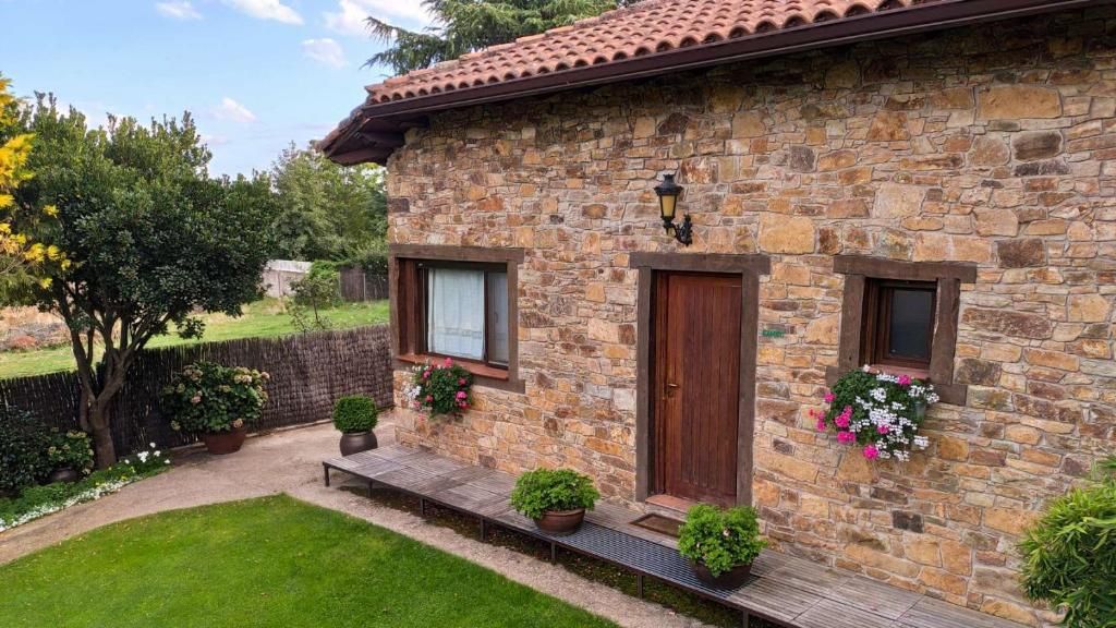 Una casa de piedra con techo de tejas, dos ventanas y una puerta de madera.