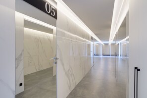 A modern hallway with marble walls and a number '05' sign, leading to a room with a door.