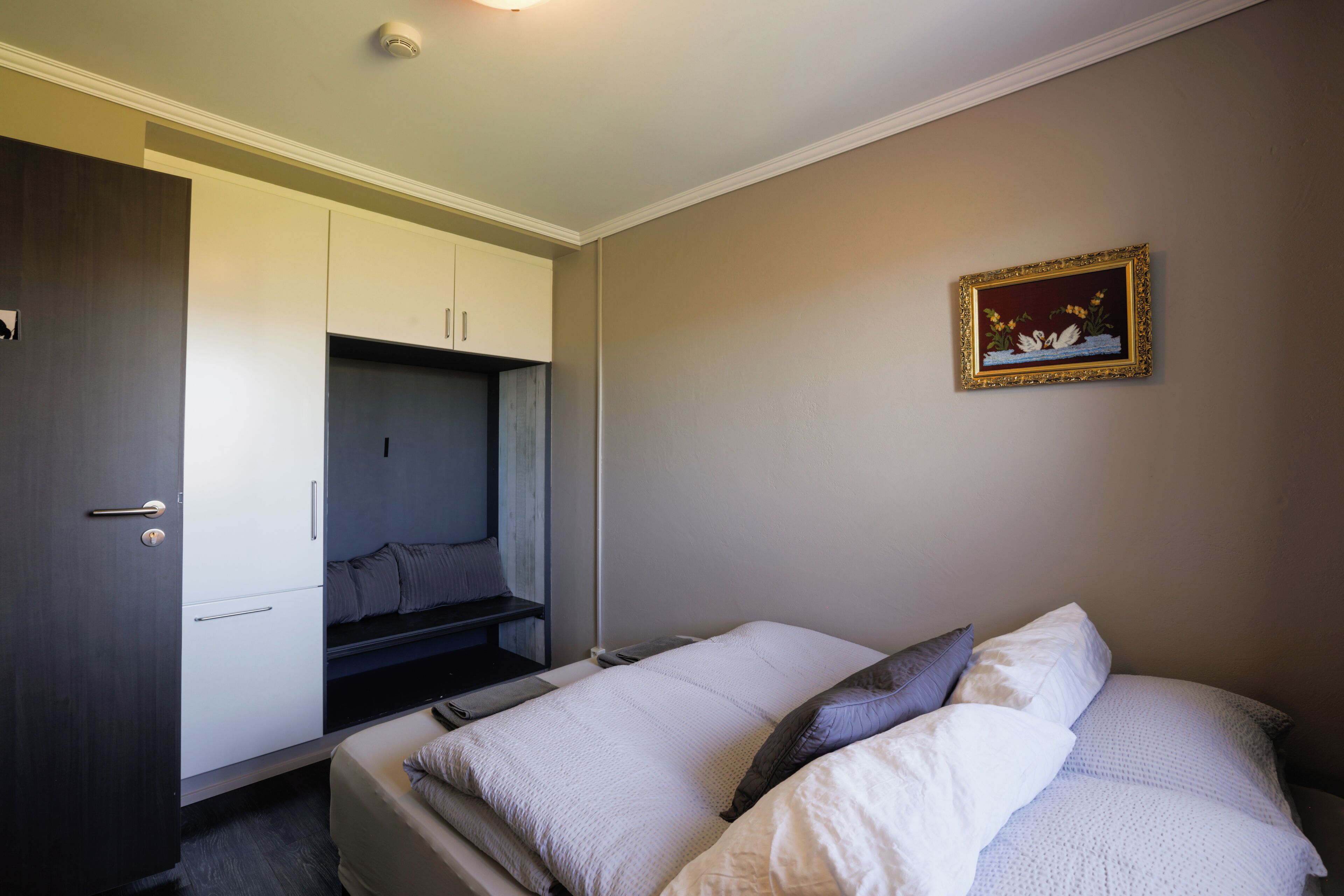 A bedroom with a bed, a wardrobe, and a small seating area.