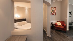 A modern hotel room with a bed, a red armchair, and a painting on the wall. - Karuna Guesthouse (Skagafjörour)