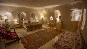 Une pièce confortable et bien éclairée, avec un lit, deux fauteuils, un canapé et une lampe sur pied.