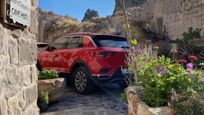 Un SUV rouge était garé devant l’entrée de l’hôtel troglodyte, un chemin de pierres menant à l’intérieur.