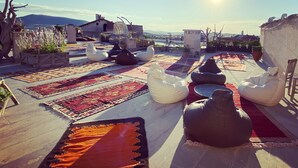 Une terrasse sur le toit, aménagée avec des espaces de détente en plein air, des tapis et des plantes en pot.