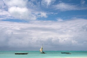 Mar calma com um veleiro e um barco a remo.