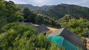 Een bergachtig landschap met meerdere gebouwen met groene daken, waarschijnlijk onderdeel van een resort of lodge.