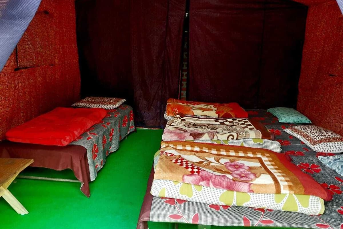 A tent-like room with multiple beds, each with a distinct patterned blanket.