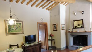 A living room with a television, wooden furniture, a fireplace, and framed pictures on the wall. - Agriturismo Montereggi (Fiesole)