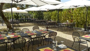 An outdoor dining area with tables and chairs, umbrellas, and a gravel ground. - Agriturismo Montereggi (Fiesole)
