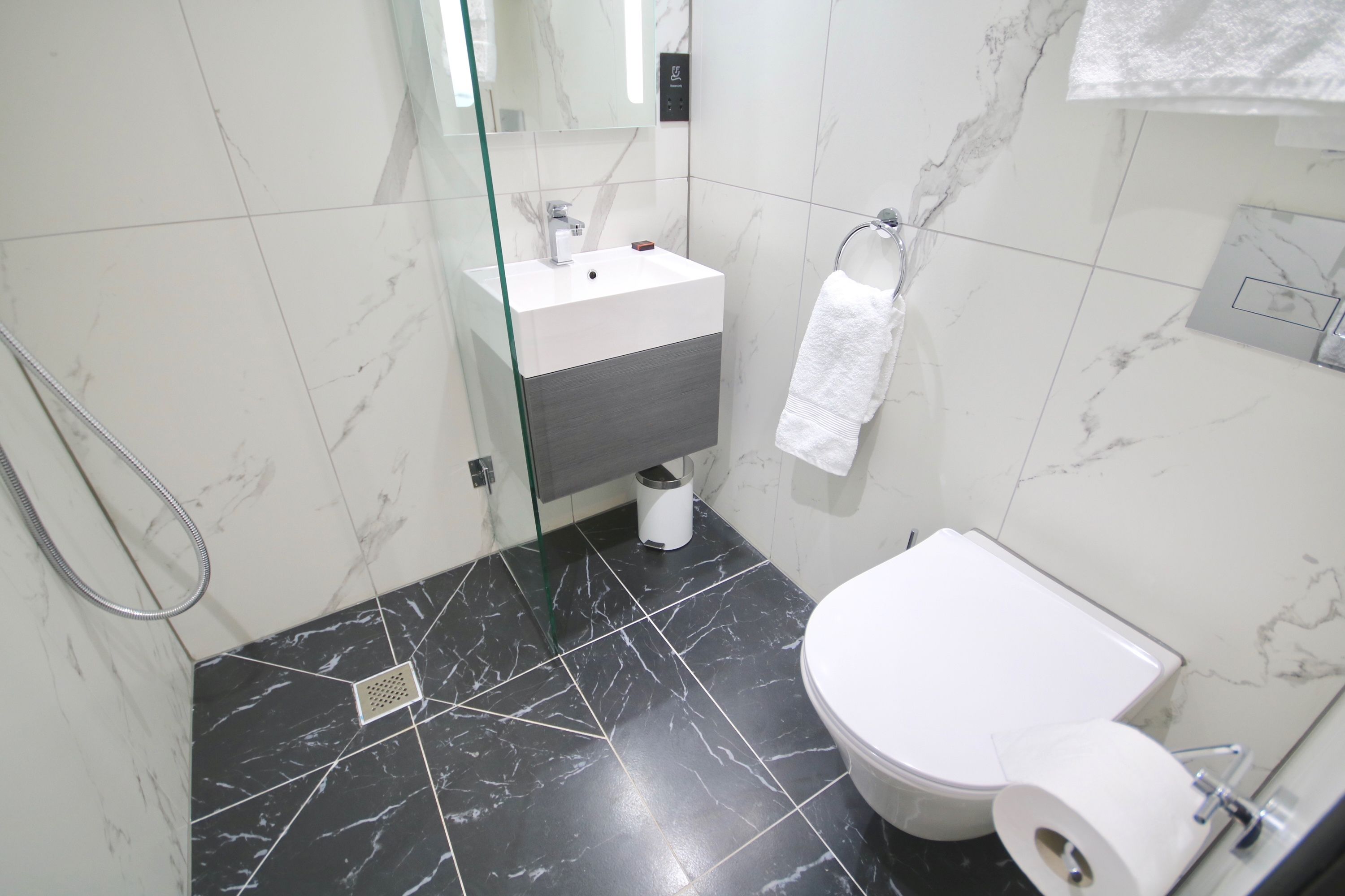 A modern bathroom with a white sink, a toilet, and a glass shower enclosure.