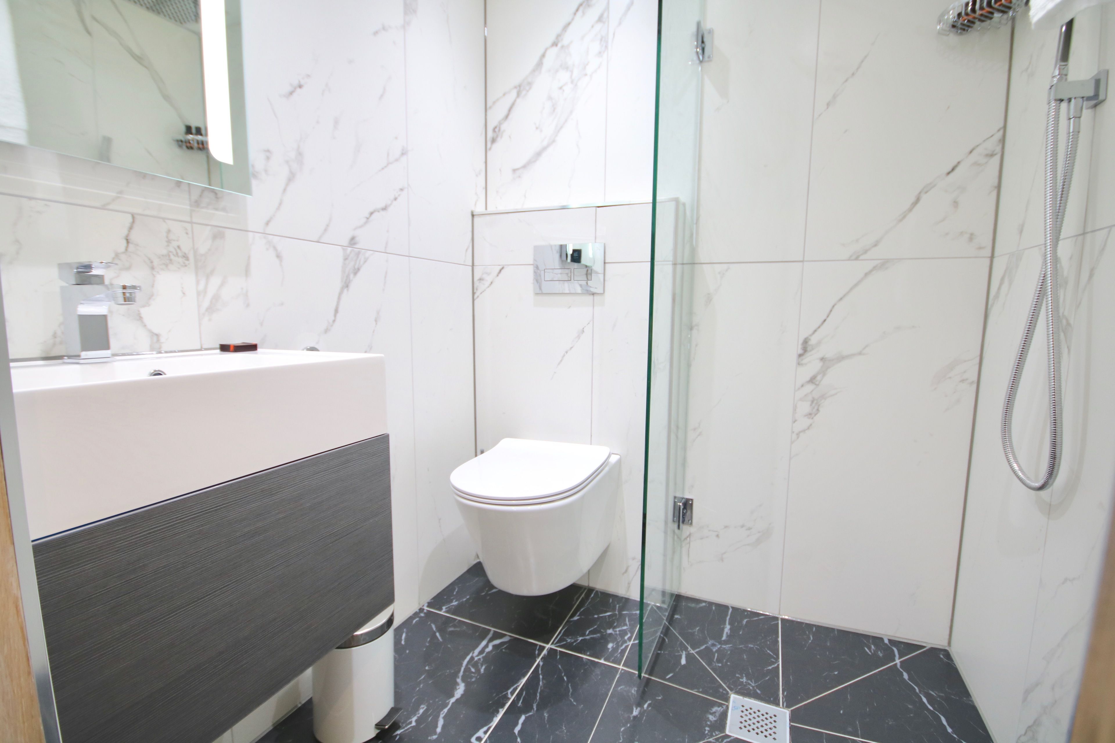 A modern bathroom with a toilet, shower, and a glass-enclosed shower area.