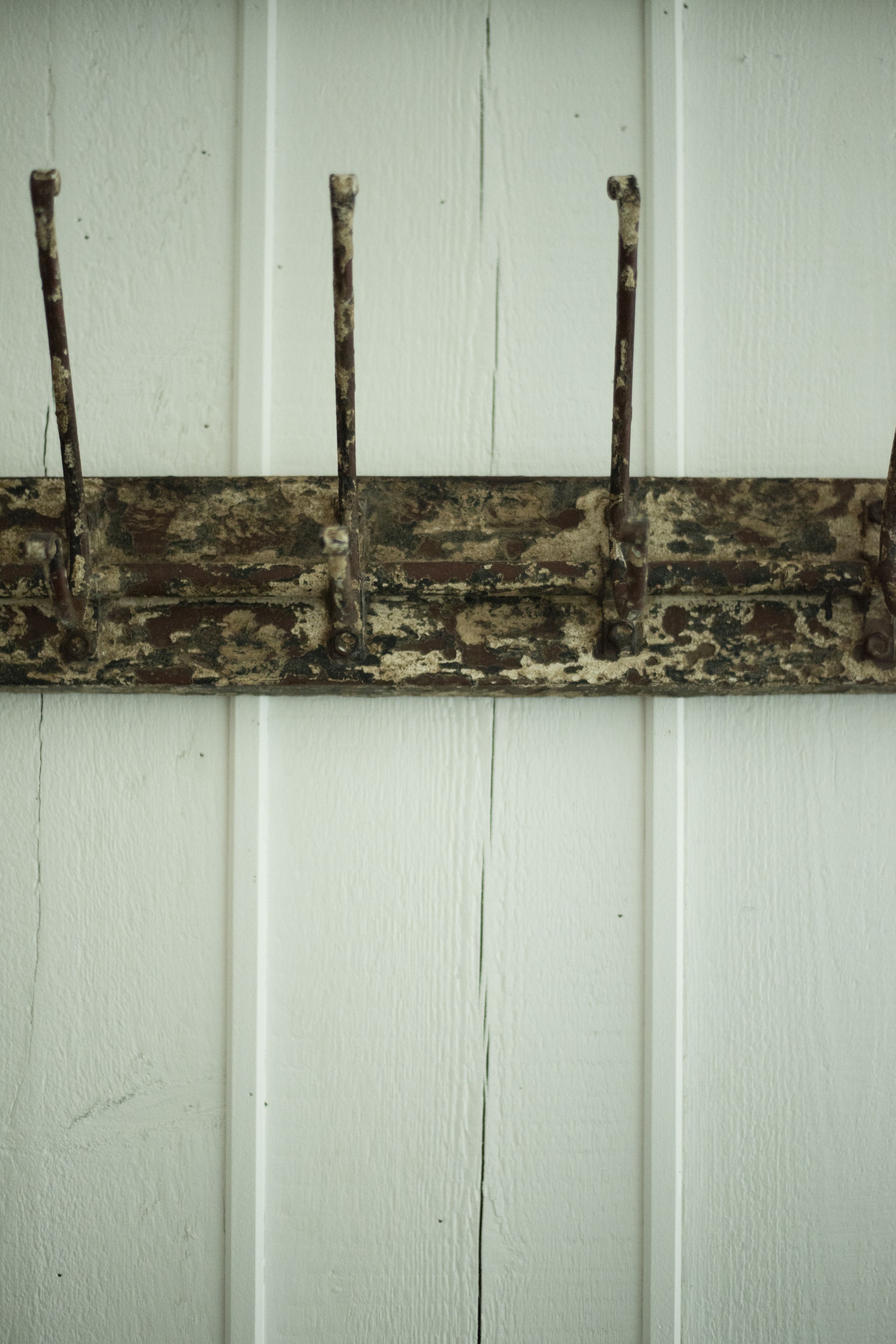 A rustic metal coat rack against a white wall.