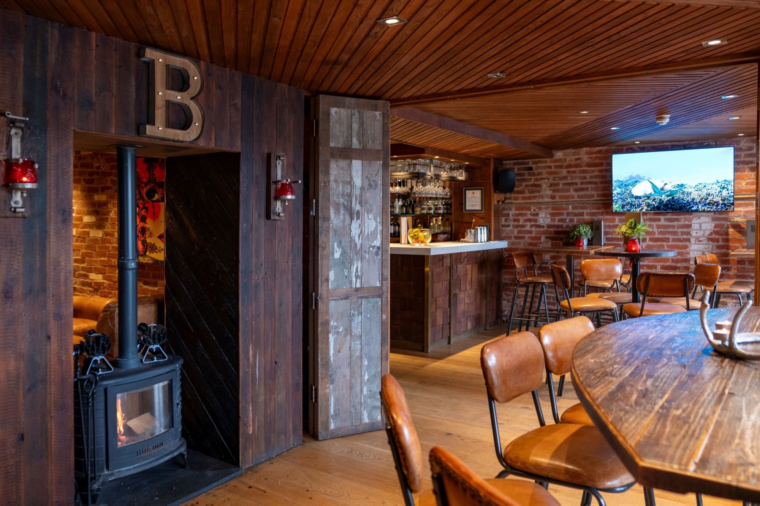 Un intérieur chaleureux avec un poêle à bois, un coin bar et un espace repas comprenant des chaises et une table.