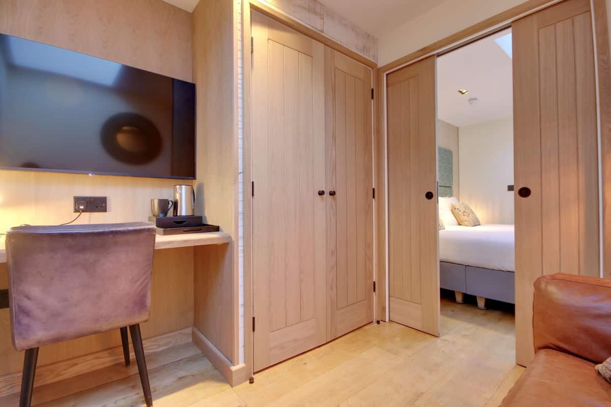 A modern room with a wooden desk, a chair, a bed, and a brown leather sofa.