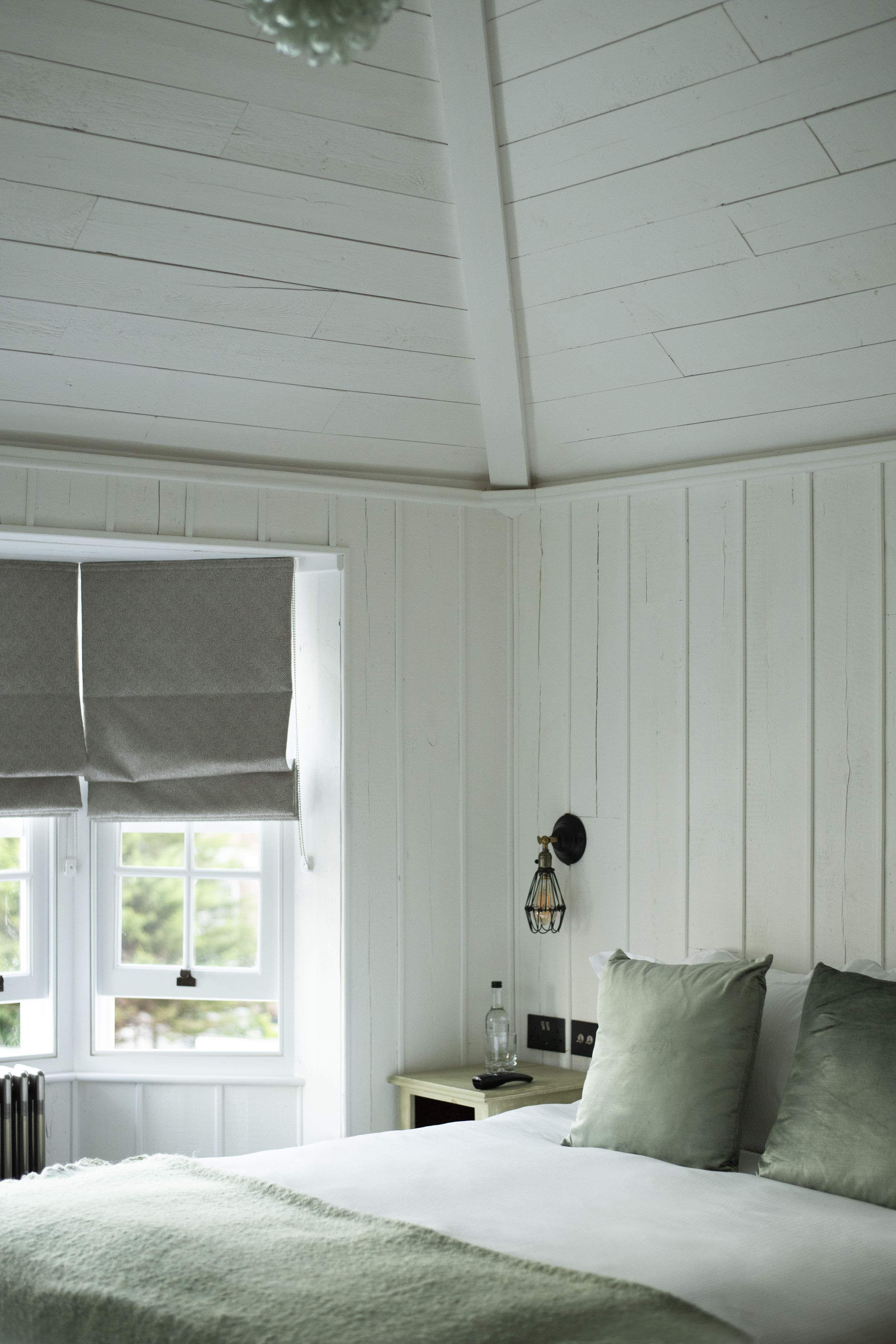A bedroom with a bed, a nightstand, a lamp, and a window with blinds.
