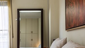 Camera d'albergo con un letto grande, un armadio, un condizionatore e un quadro appeso al muro.