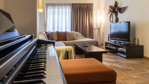 Un soggiorno con un pianoforte, un divano, una televisione e un uccello decorativo appeso al muro.