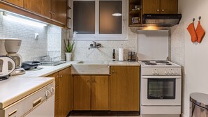 Una cucina compatta con mobili in legno, un piano cottura bianco, un lavello e una finestra sopra il bancone.