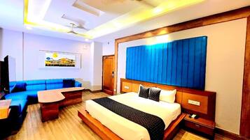 Una habitación de hotel con una cama grande, un sofá, una mesita y un ventilador de techo.