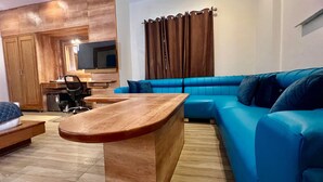 Una sala de estar moderna con una mesa de centro de madera, un sofá azul y un escritorio de madera con una silla.
