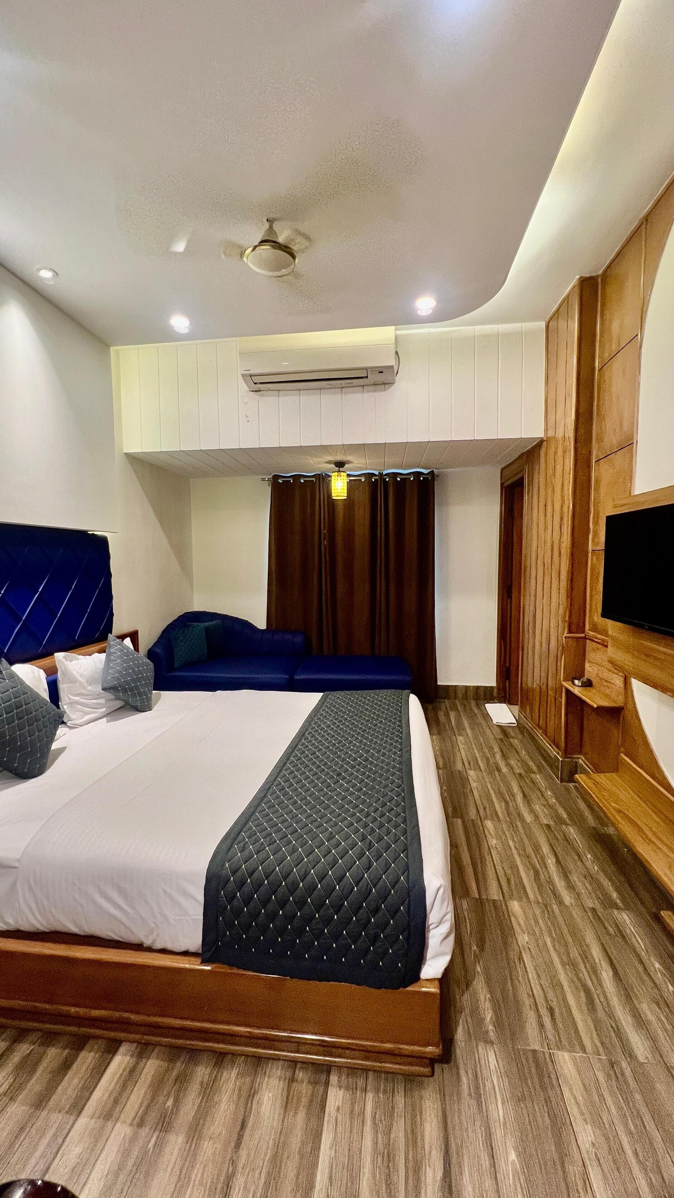 A modern hotel room with a large bed, a TV, and an air conditioning unit.