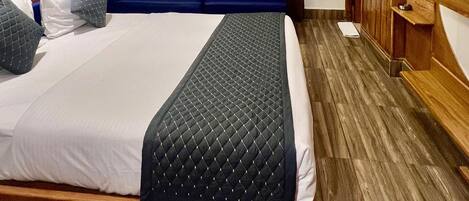 A modern hotel room with a large bed, a TV, and an air conditioning unit.